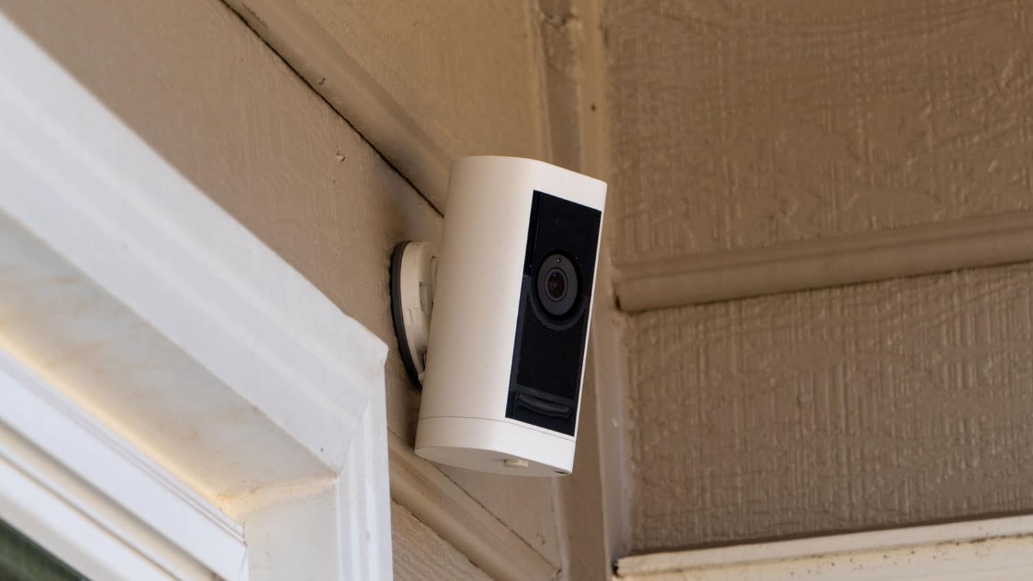 Outdoor home security camera mounted beside an exterior doorway