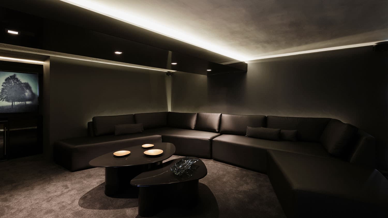 Dark home theater room with sectional seating and recessed accent lighting