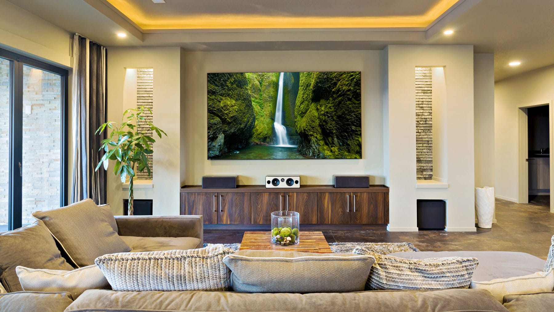 Home theater room with a large wall-mounted TV, speakers and sectional seating