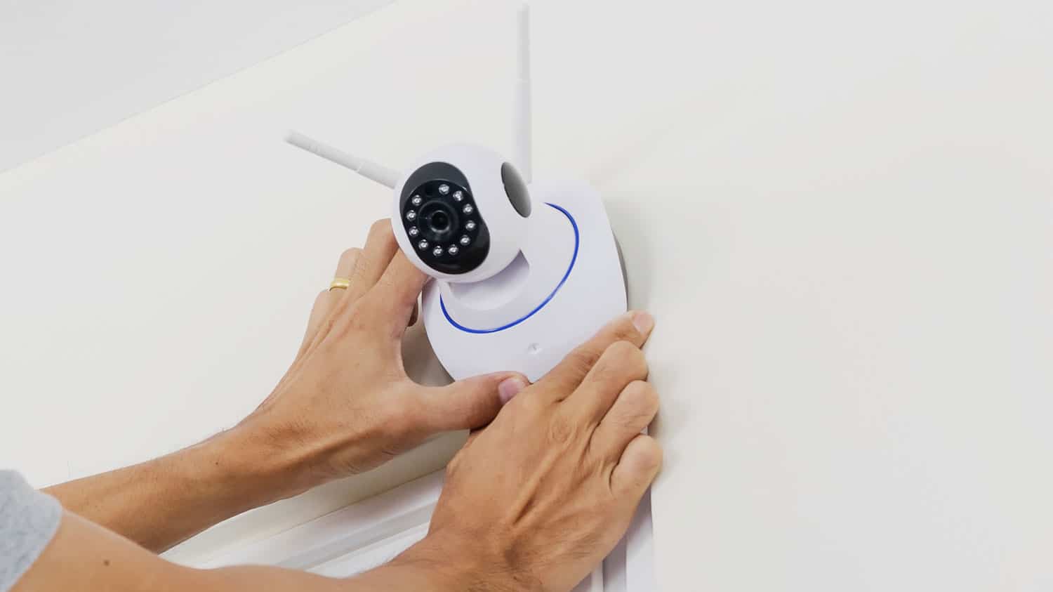 Person installing a wireless home security camera on an interior wall